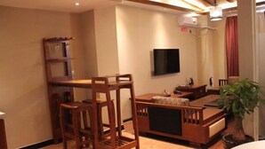 A living room with a TV mounted on the wall, a wooden coffee table, and a sofa. - Yiyuan Impression Inn (Eryuan)