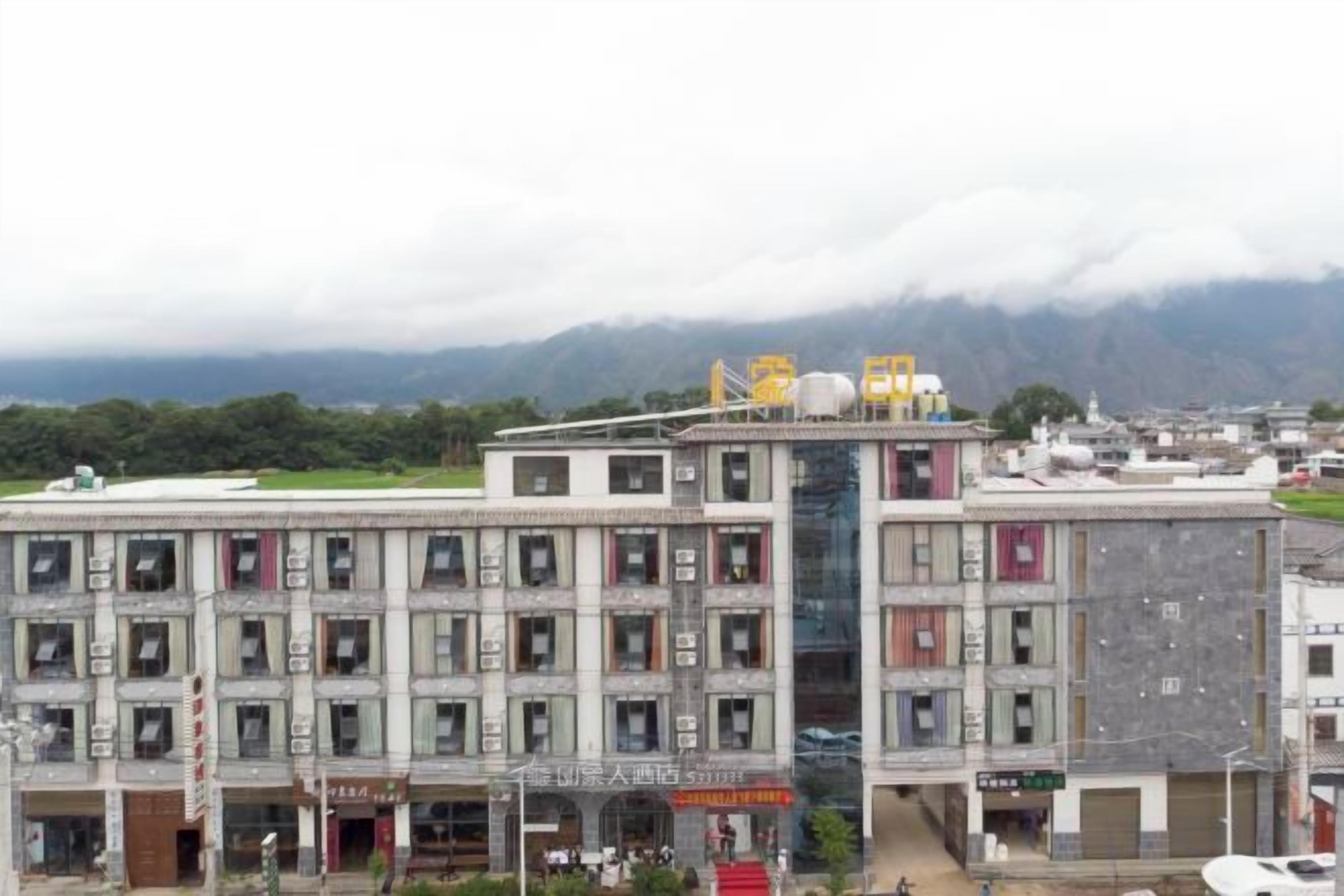 Un edificio de varios pisos con techo plano y múltiples ventanas, con señalización.