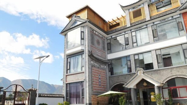 Un edificio de varios pisos con un estilo arquitectónico tradicional, con ventanas amplias y un balcón con barandilla de madera.