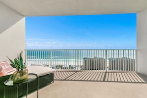 A balcony with a view of the ocean and buildings.
