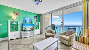 A bright living room with a green wall, a TV, a coffee table, and a sofa. - Majestic Beach Towers 1-2013 (Panama City Beach)