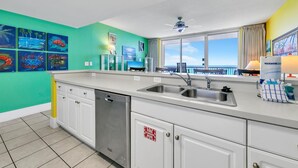 A modern kitchen with a large window, a dishwasher, and a sink. - Majestic Beach Towers 1-2013 (Panama City Beach)