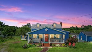 A two-story blue house with a front porch, a small garden, and a pathway leading to the entrance.