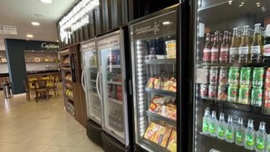 A refrigerated display case with various food items and beverages, including bottled water and snacks. - Flórida Mall & Suites (Limeira)
