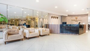 Un hall d’hôtel avec des canapés, un comptoir d’accueil et un grand miroir qui reflète l’intérieur.