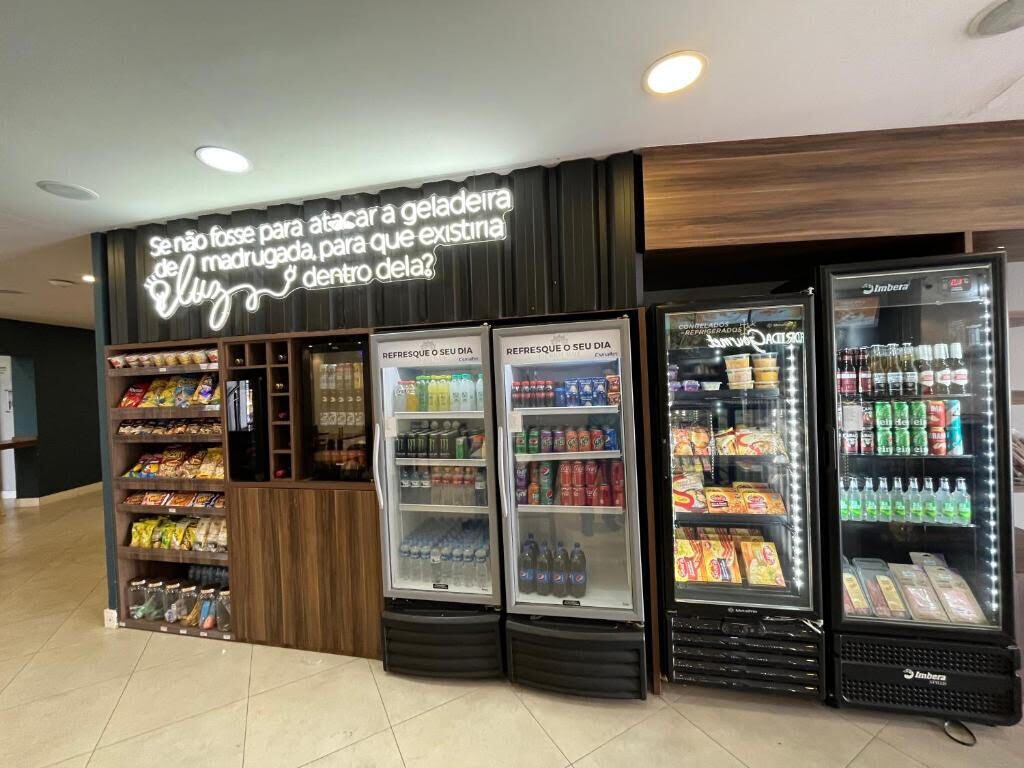 A snack bar with refrigerated drink dispensers and shelves stocked with snacks.