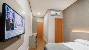 Une chambre d’hôtel équipée d’un lit, d’un bureau, d’un téléviseur fixé au mur et d’un appareil de climatisation.