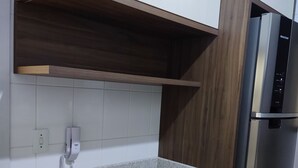 A kitchen with a granite countertop, two black office chairs, a stainless steel refrigerator, and a phone on the wall. - Apartamento Completo Mobiliado com ar Condicionado Quente Frio (Country Cascavel)