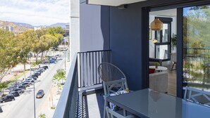 Ein Balkon mit Blick auf eine Straße und parkende Autos, ein Stuhl und ein Tisch.