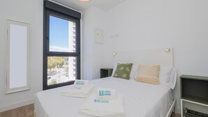 Ein Hotelzimmer mit Bett, Nachttisch, Fenster und einer Hängelampe.