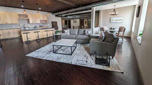 A spacious living area with a dark hardwood floor, a ceiling fan, a gray sofa, and a coffee table.