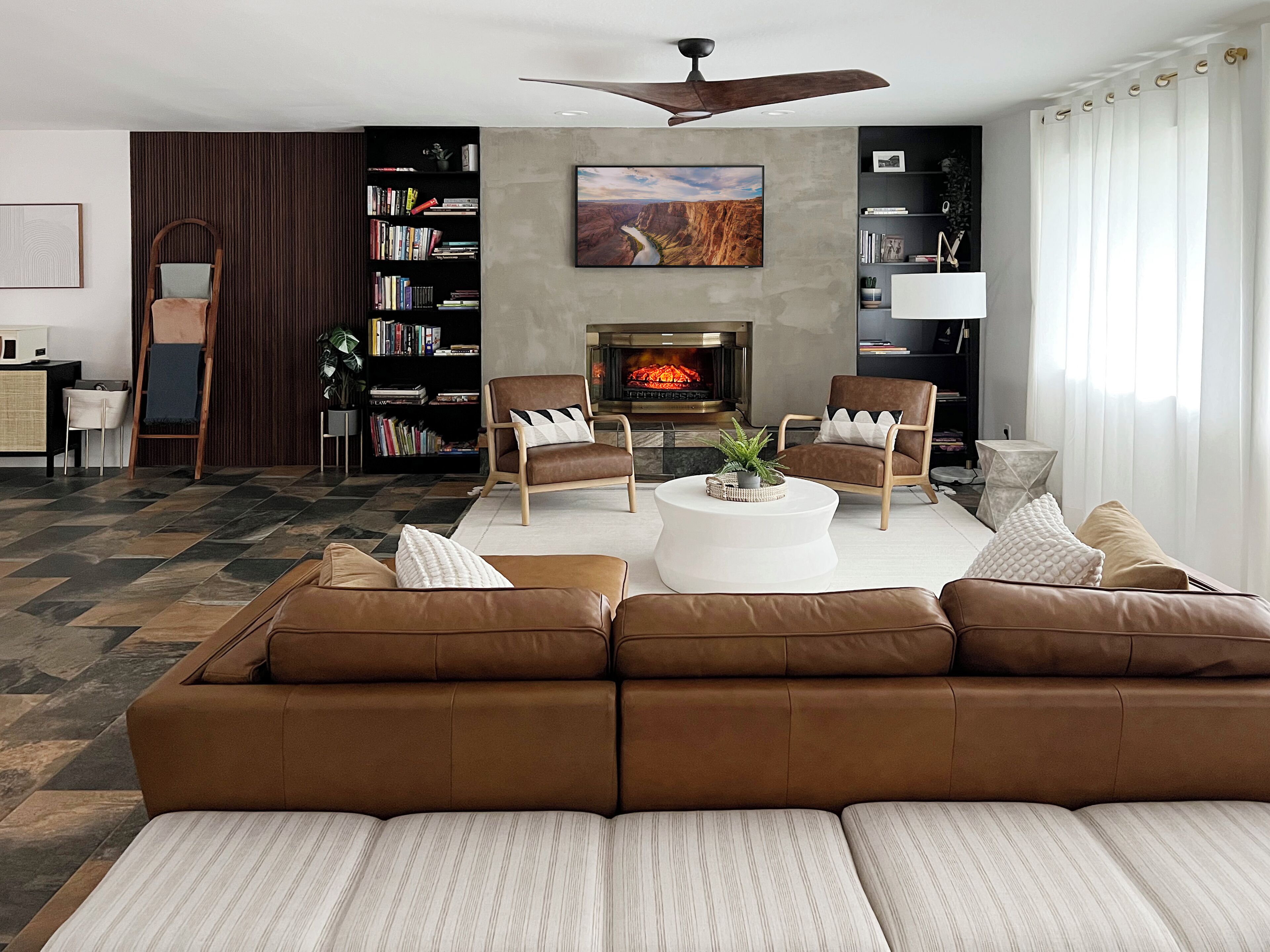 A modern living room with a brown leather sofa, a white coffee table, and a fireplace.
