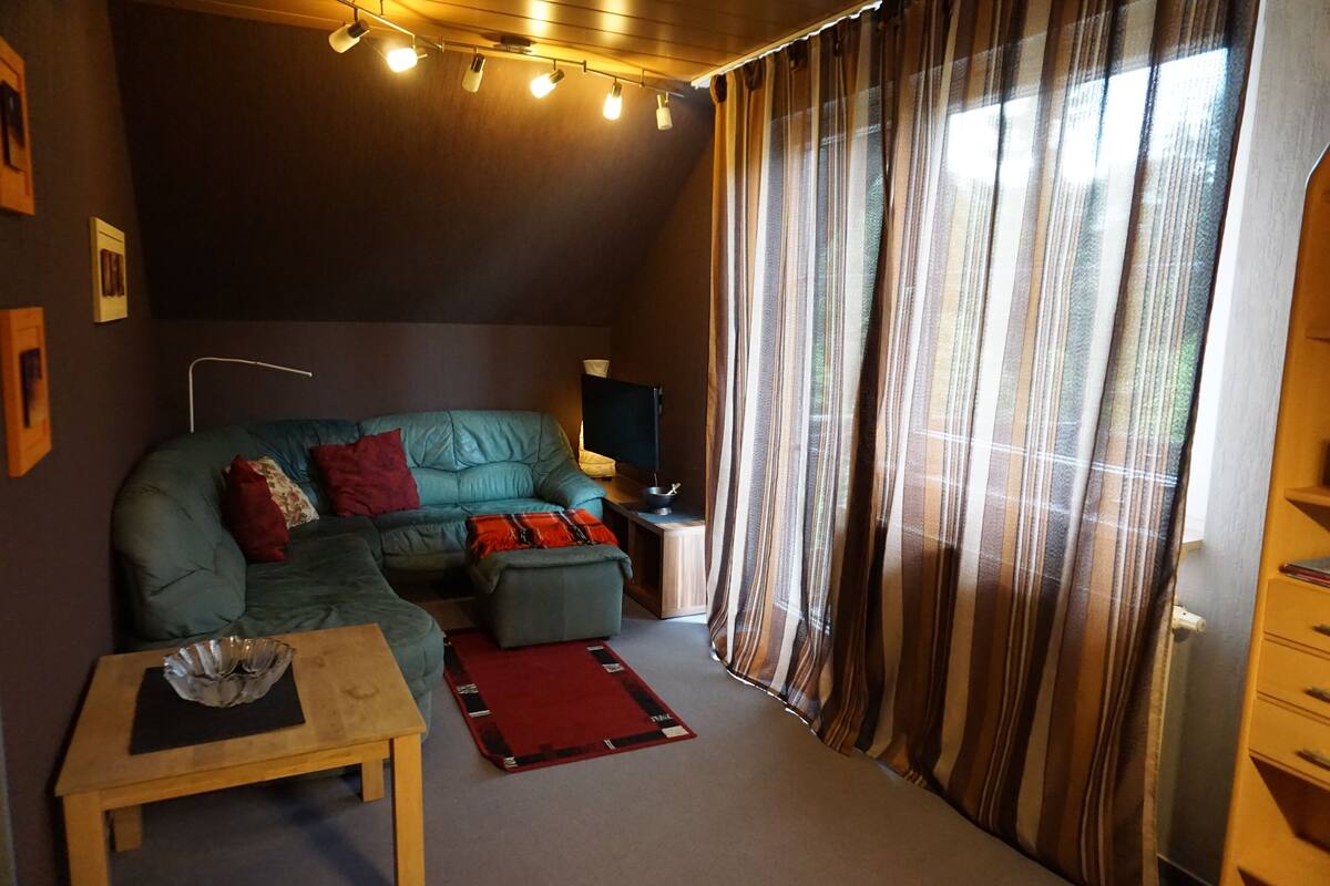 A cozy living room with a sectional sofa, a small table, and a red rug.