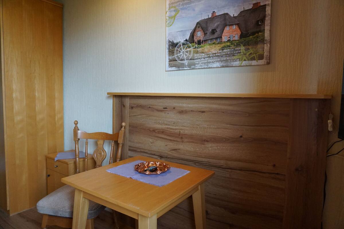 A wooden dining table with a placemat, a chair, and a small wooden cabinet.