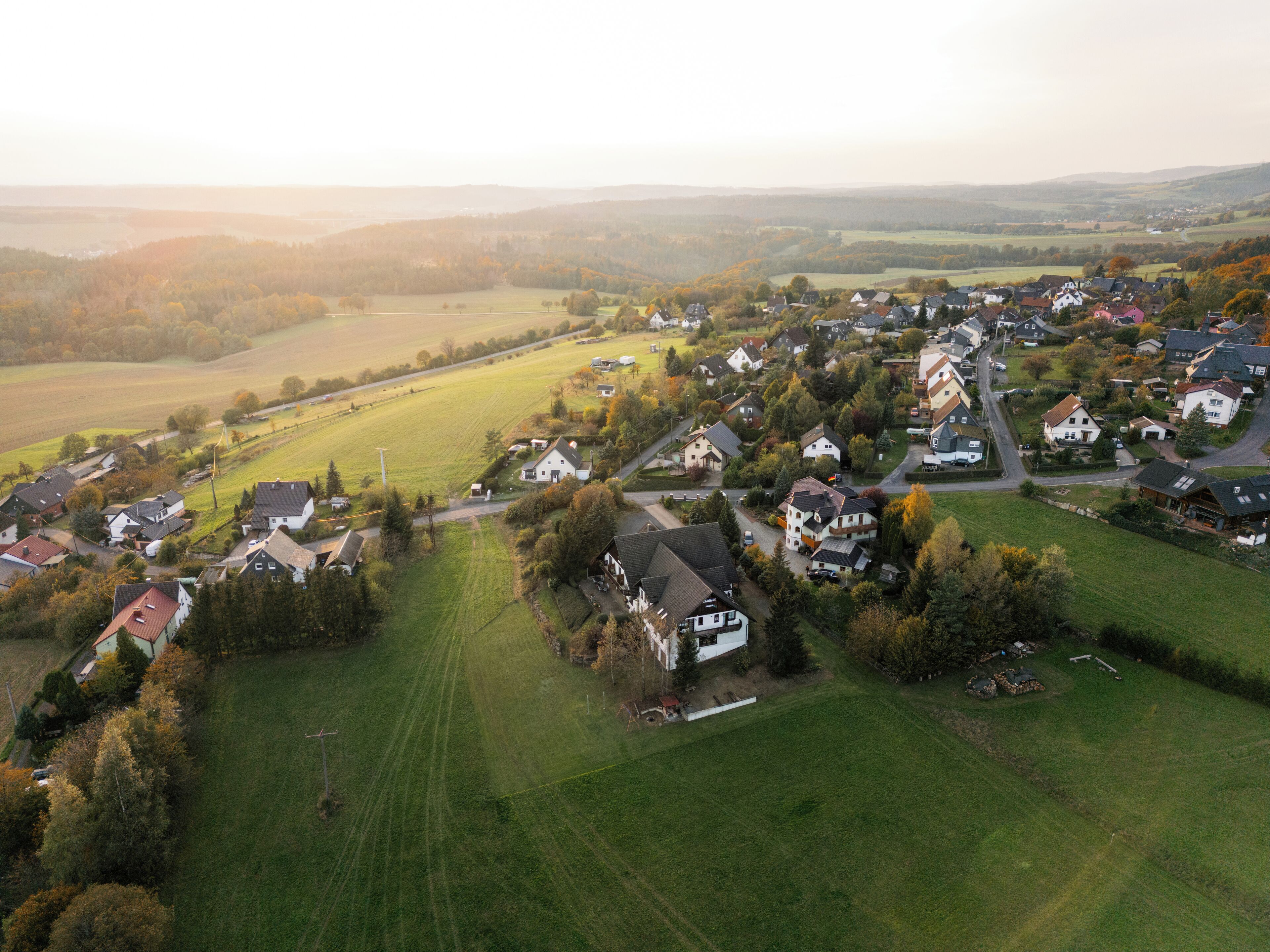 Luchtbeeld van een landelijk dorp met huizen, wegen en velden.