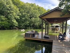 A wooden dock extending into a green body of water, with a covered seating area and a boat. - Waterfront dog-friendly home with private dock, kayaks, WiFi, AC (Goodview)