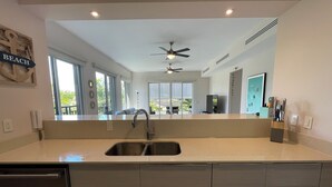 A modern kitchen with a large island, stainless steel sink, and a ceiling fan. - Harmony Lush Refuge 3BR Laguna (Río Hato)