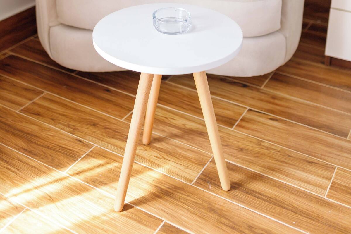 A beige armchair with a round white table in front of it.
