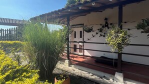 A courtyard with a tiled roof, potted plants, and a building with a white facade and dark trim. - Finca Hotel San Miguel (Calarcá)