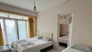 A hotel room with two beds, a desk, and a bathroom visible through an open door. - İnka Otel (Armutlu)