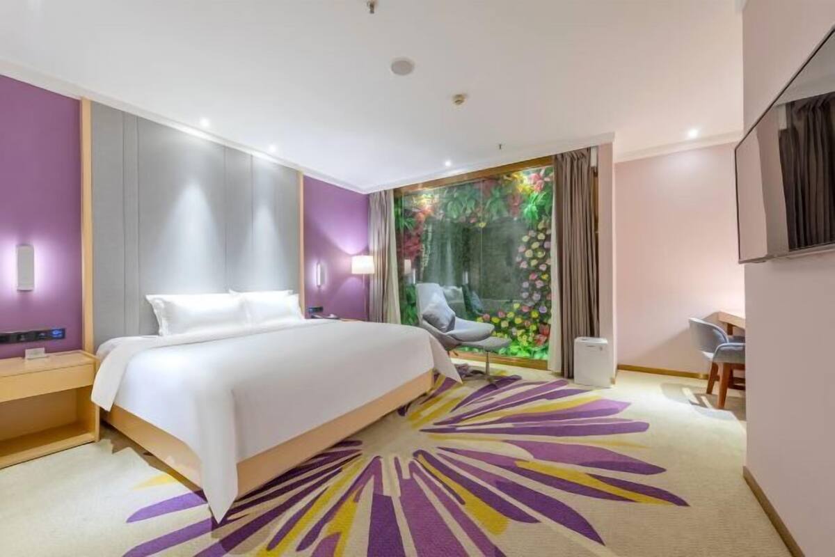 A modern hotel room with a bed, a desk, and a chair.