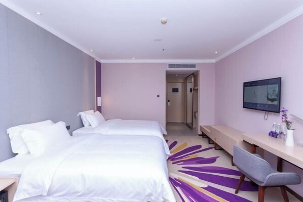 A hotel room with two beds, a desk, a chair, a TV, and a bathroom door.