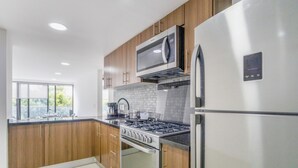 Una cocina moderna con electrodomésticos de acero inoxidable, armarios de madera y un amplio ventanal que proporciona luz natural.