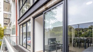 Un edificio moderno con amplios ventanales y un balcón con mobiliario de exterior.