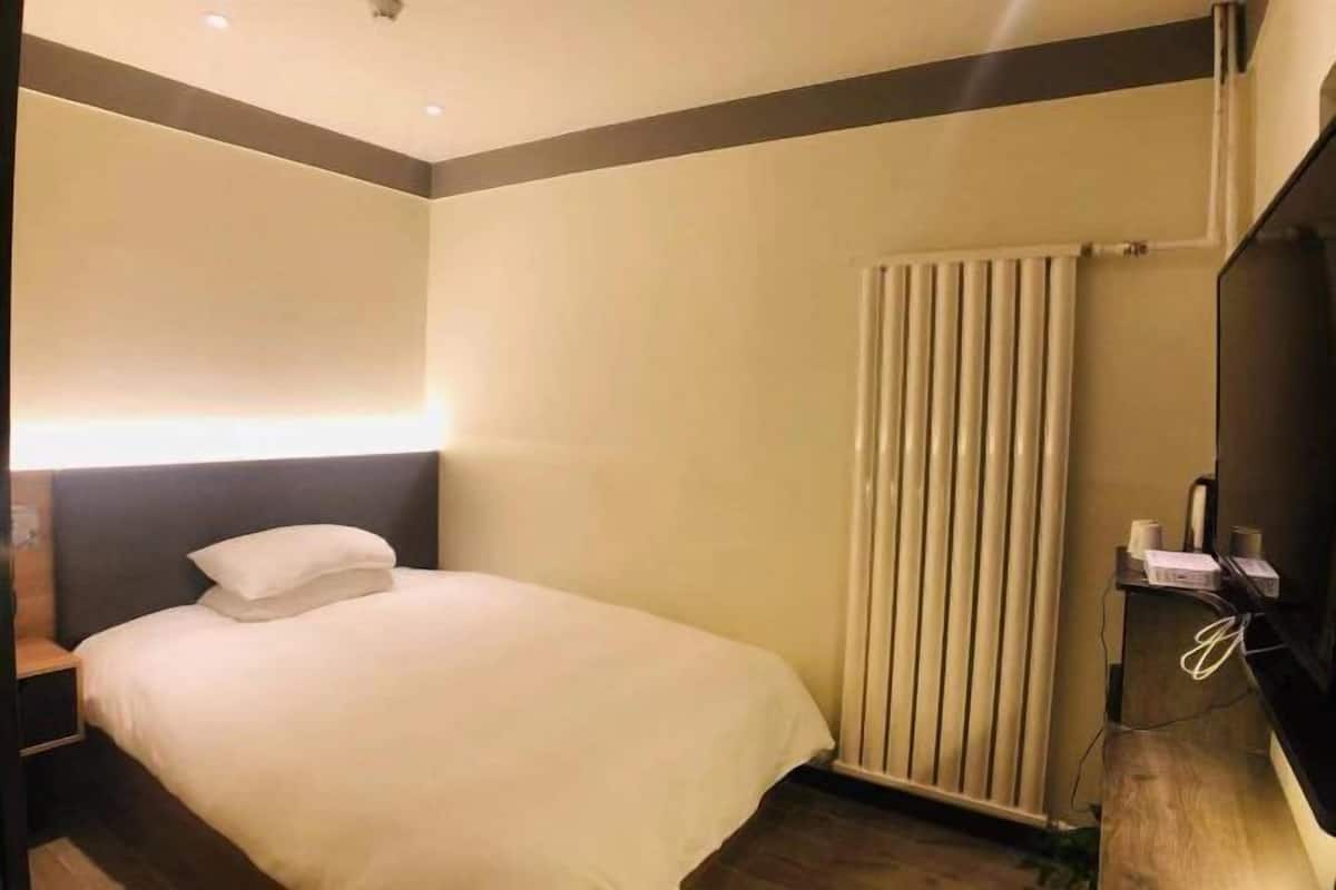 A hotel room with a bed, bedside table, and a TV.