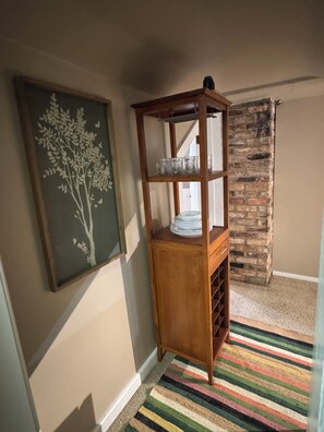 A corner room with a wooden cabinet, a framed artwork, and a brick wall.