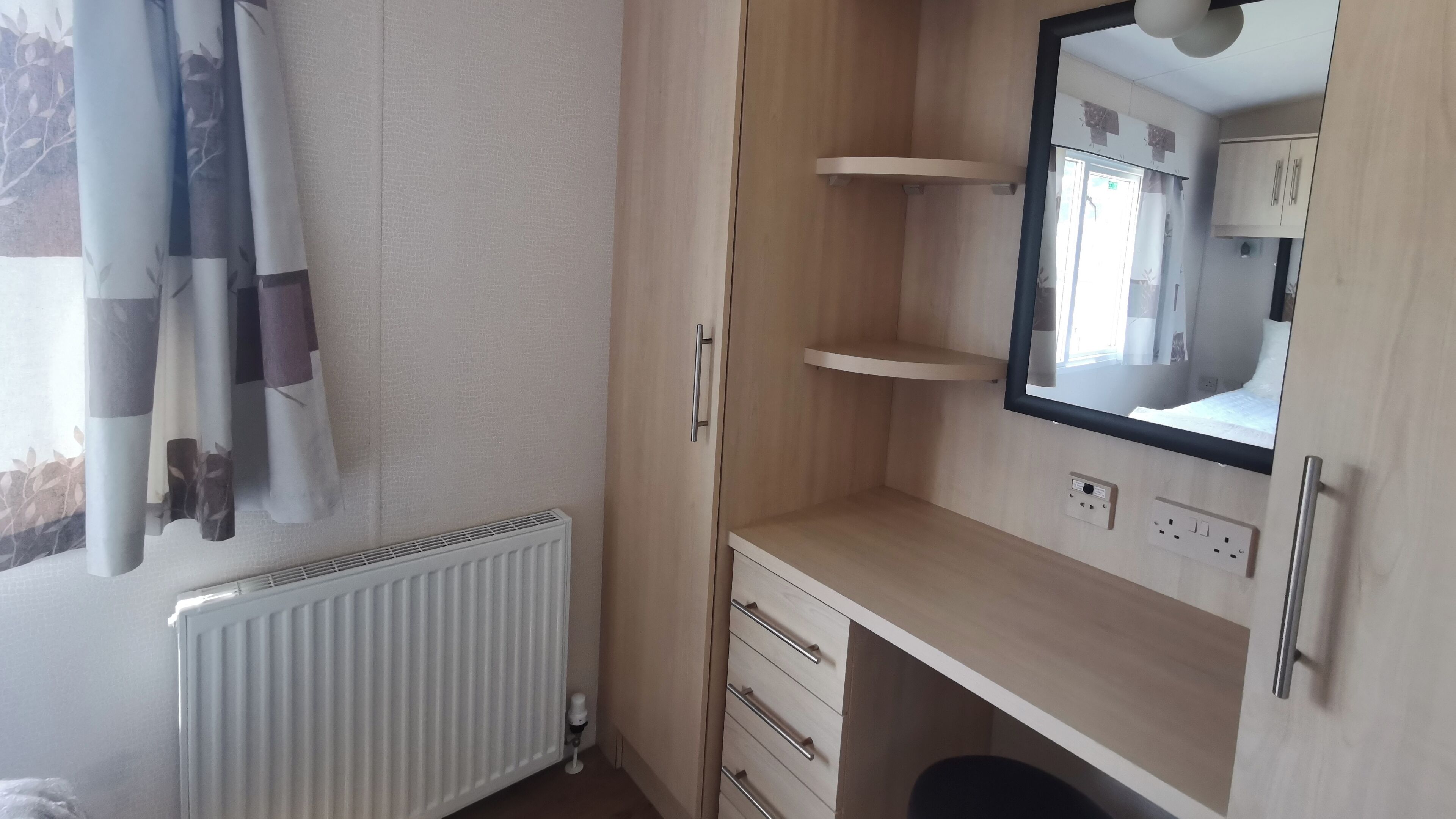 A bedroom with a wooden wardrobe, a mirror, and a radiator.