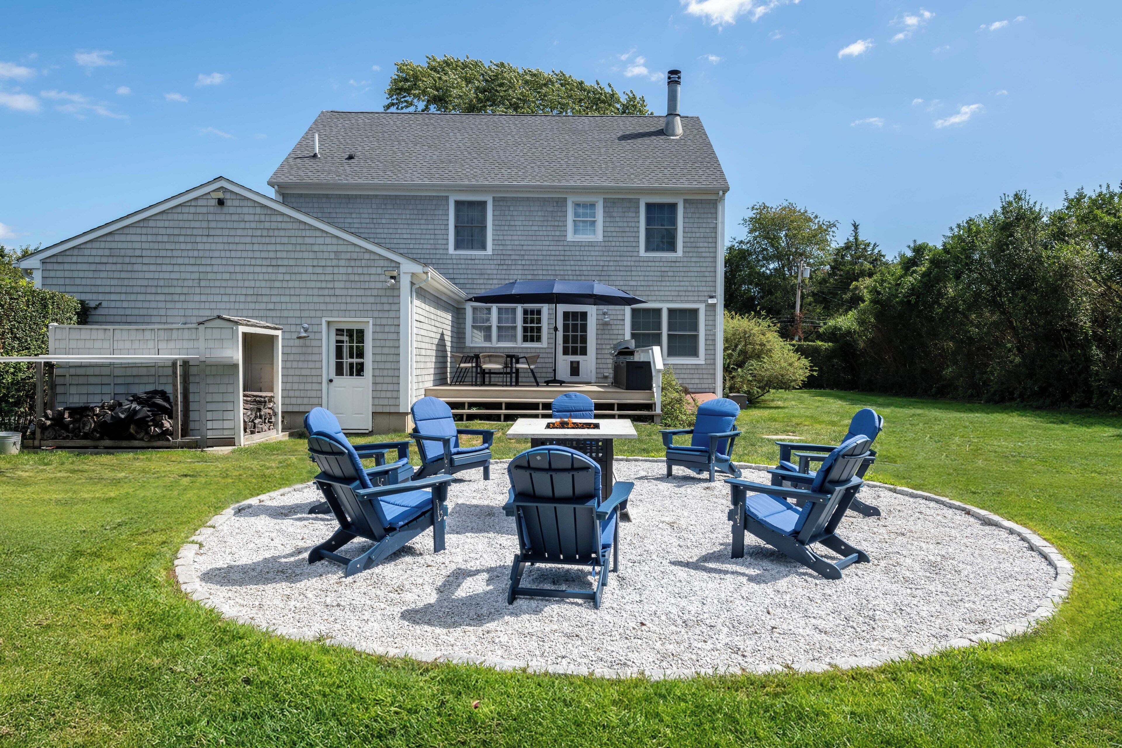 Une maison dotée d’un patio aménagé avec du mobilier d’extérieur et un barbecue.