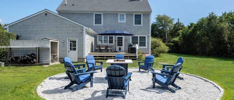 Une maison dotée d’un patio aménagé avec du mobilier d’extérieur et un barbecue.