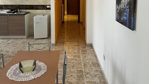 Uma cozinha moderna com área de refeições, uma geladeira e um corredor que leva a uma porta.