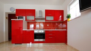 Una cucina compatta con mobili rossi, forno integrato e microonde.
