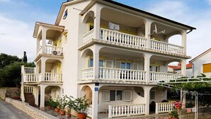 Un edificio a più piani con balconi, piante in vaso e un vialetto in pietra.