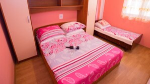 Camera da letto con due letti, pareti rosa e un armadio in legno.