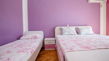 A bedroom with two single beds, a nightstand, and an air conditioning unit.