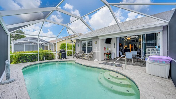 Ein überdachter Außenpool mit Terrasse, Stühlen und Grill.