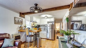 A kitchen with white cabinets, stainless steel appliances, and a wooden dining table. - North Georgia Fall Escape for Hunting & Fishing (Ranger)