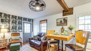 A cozy living room with a brown leather sofa, a wooden dining table, and a green ottoman. - North Georgia Fall Escape for Hunting & Fishing (Ranger)