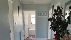 A hallway with a checkered floor, a white table with a plant, and a chandelier. - Farmer's Cottage (Nenagh)