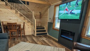 Un interior de madera con televisor, escalera y zona de estar.