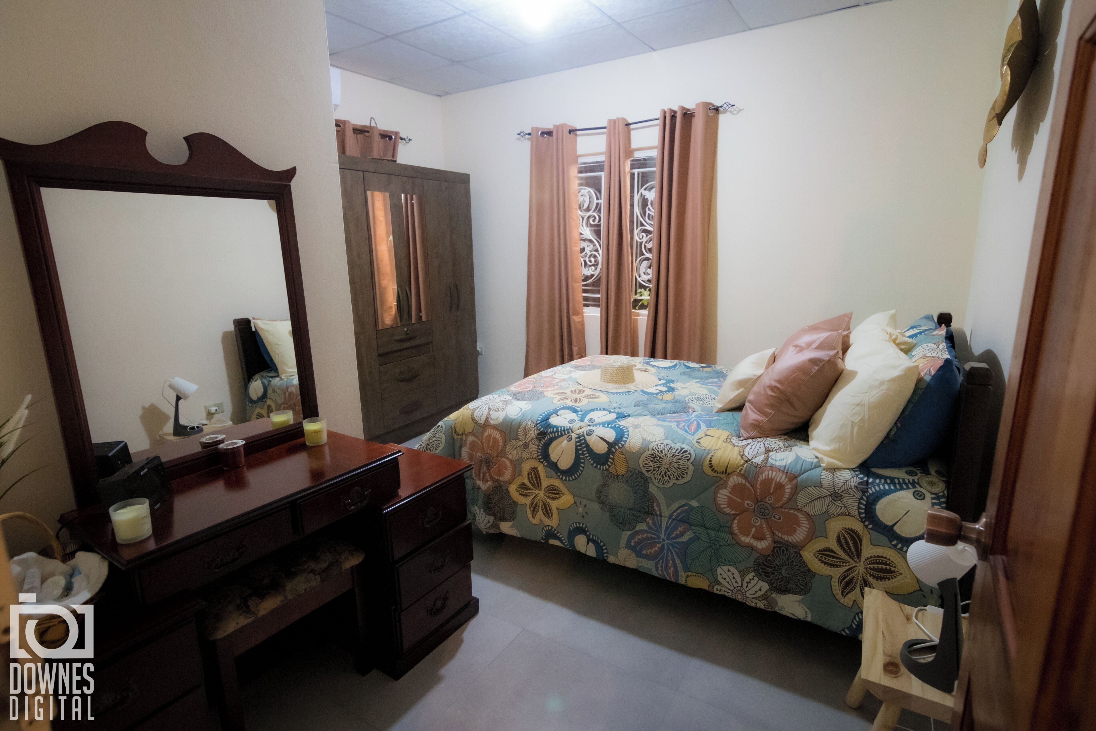 A bedroom with a bed, a dresser, a mirror, and a wardrobe.