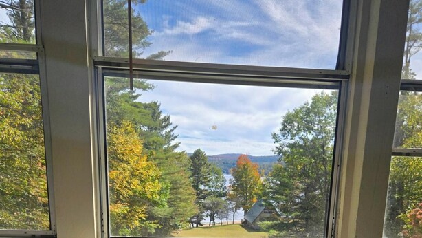 A window with a view of trees and a house. - Cozy 2-bdrm, 3-season Adirondack cabin at tranquil Great Sacandaga Lake w/WiFi (Hadley)
