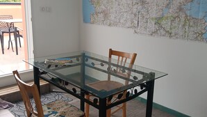A dining area with a glass-top table, two wooden chairs, and a large map on the wall. - Apartment 34m2 large terrace sea view 2km beaches gr34. Pink granite hillsides (Trelevern)