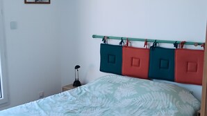 A bedroom with a bed, a nightstand, a lamp, and a wall-mounted shelf. - Apartment 34m2 large terrace sea view 2km beaches gr34. Pink granite hillsides (Trelevern)