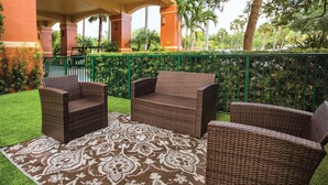 A patio area with wicker furniture and a patterned rug.
