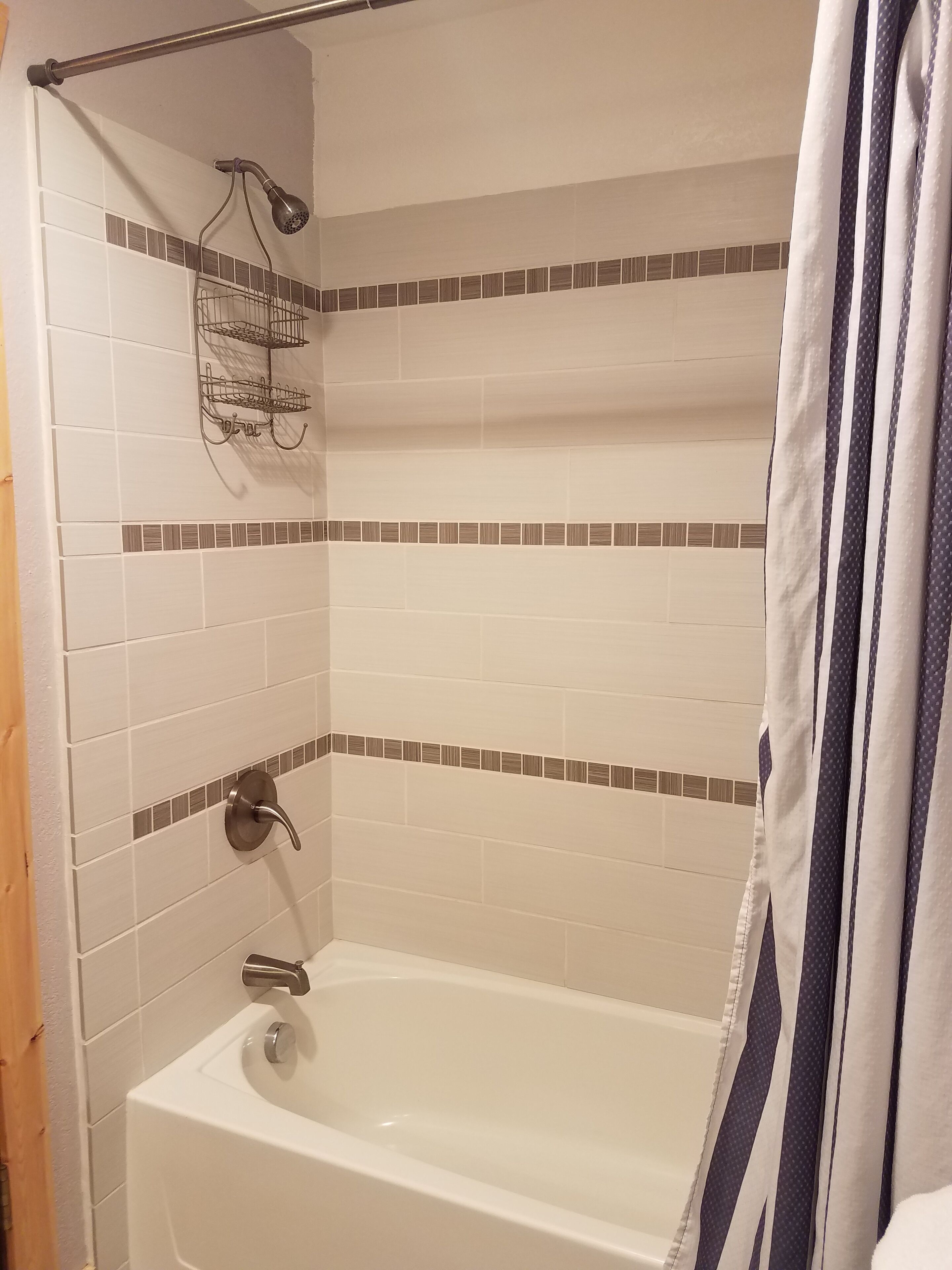A bathroom with a bathtub, a showerhead, and a towel rack.