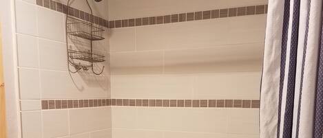 A bathroom with a bathtub, a showerhead, and a towel rack.